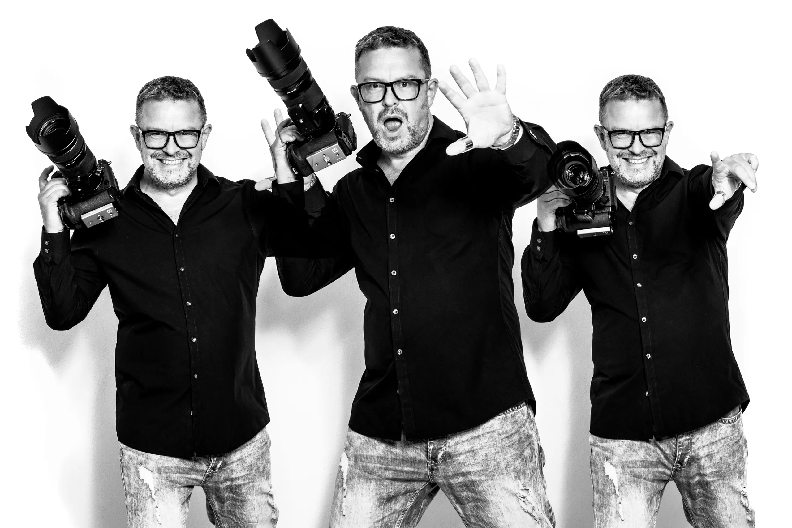 Jens Achtert dreifach in Schwarzweiß vor weißem Hintergrund, mit Kameras in der Hand · Businessfotograf und Regisseur · imagecouture