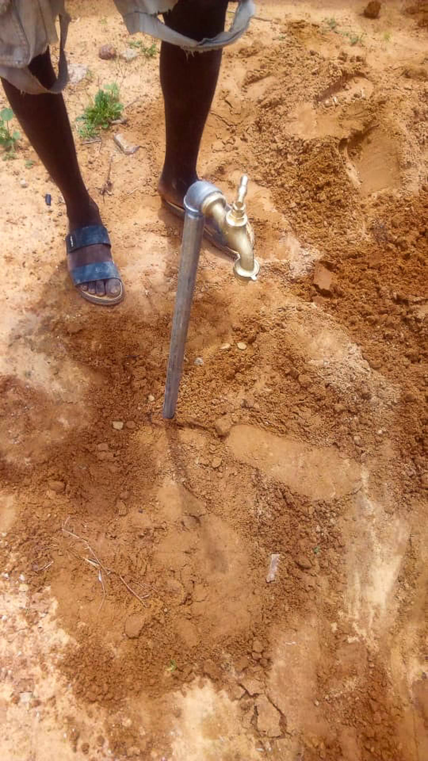 Der erste fertig installierte Wasserhahn des Projekts #waterforzinder ragt aus dem Sandboden in Zinder, Niger