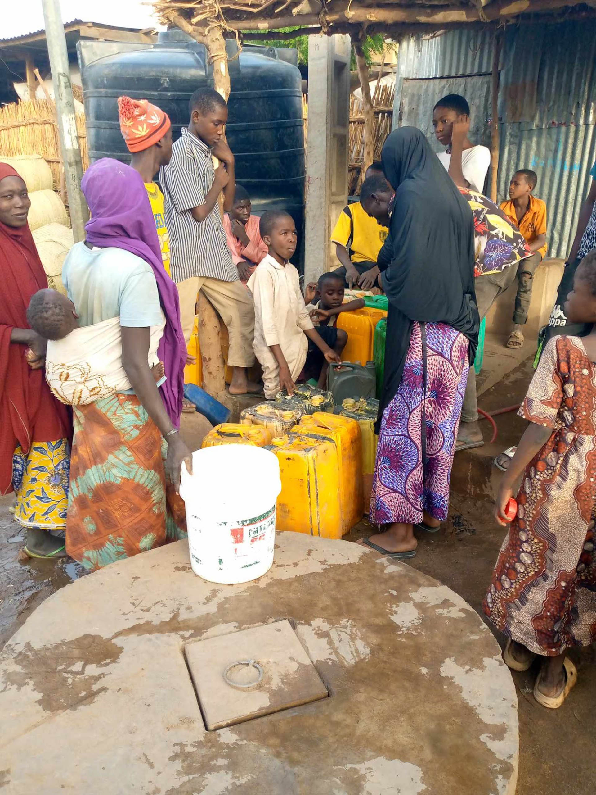 Familien mit gelben Kanistern an der Wasserausgabe des Tanks in Zinder, Niger · Projekt #waterforzinder
